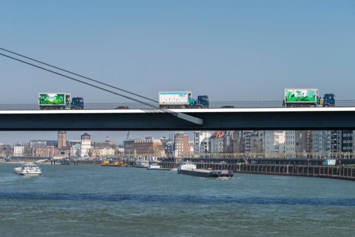 Drei LKWs auf einer Brücke über einem Fluss, zeigt die Mobilität und den Transport von Fertiggaragen.