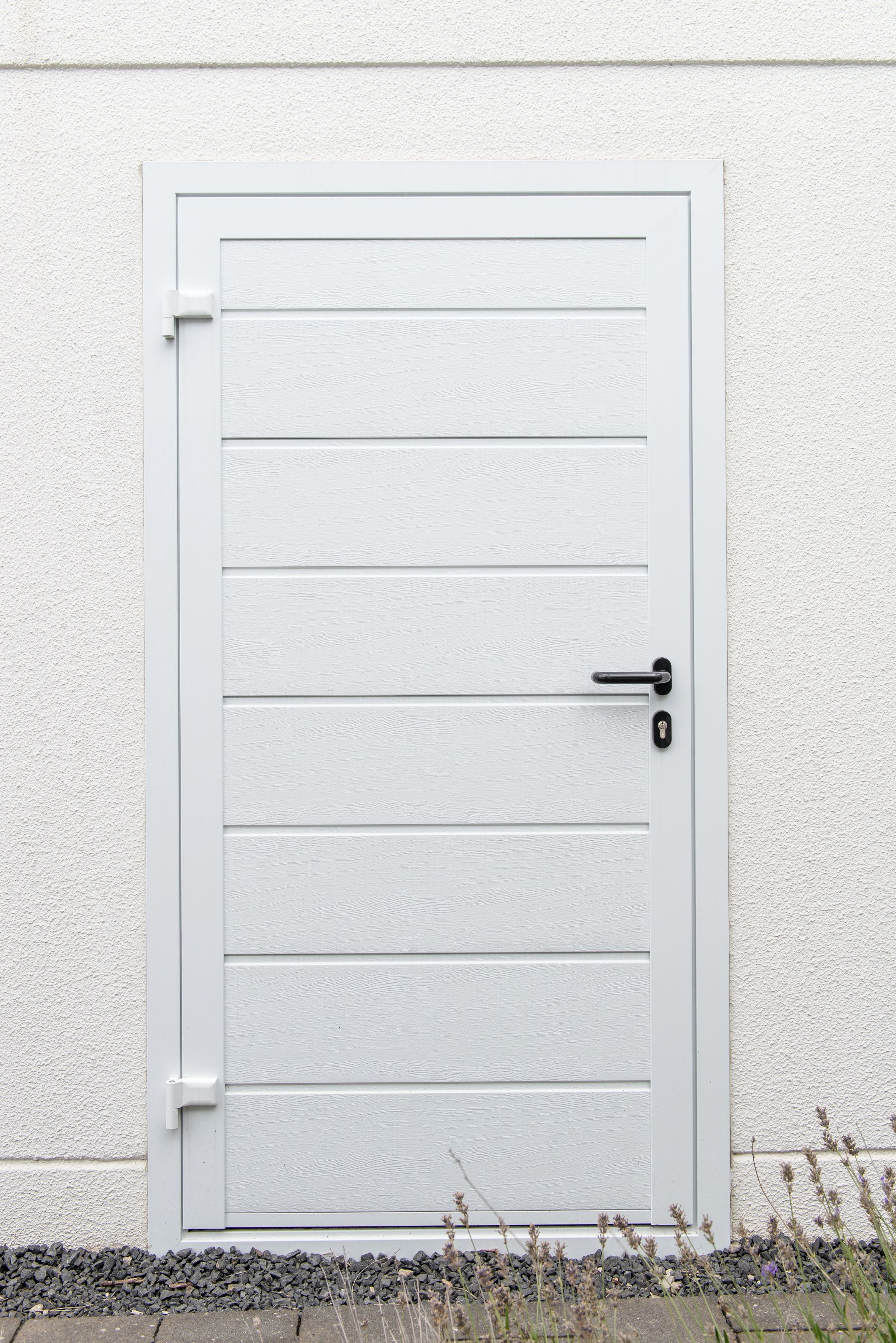 Weiße Tür mit horizontalen Paneelen in einer hellen Fertiggarage, zeigt eine praktische Nebentür für zusätzlichen Zugang.