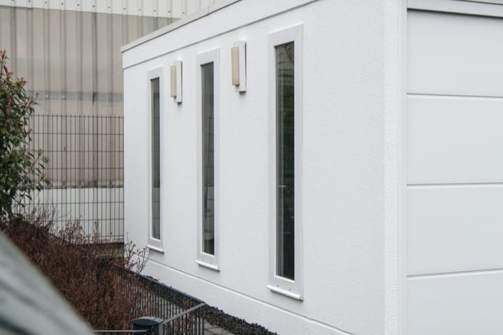 Mehrere vertikal ausgerichtete festverglaste Fenster in einer hellen Fertiggarage, die viel Tageslicht einlassen und eine moderne Optik bieten.