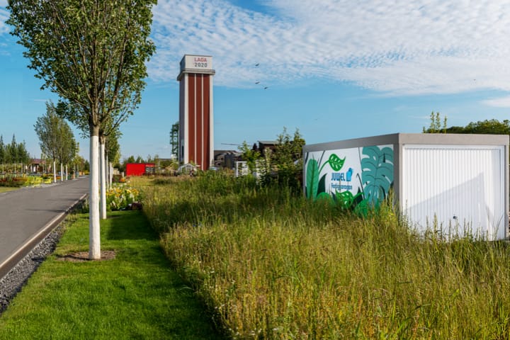 Weiße Fertiggarage mit Photovoltaikanlage in einer grünen Umgebung, betont Nachhaltigkeit und Energieeffizienz.